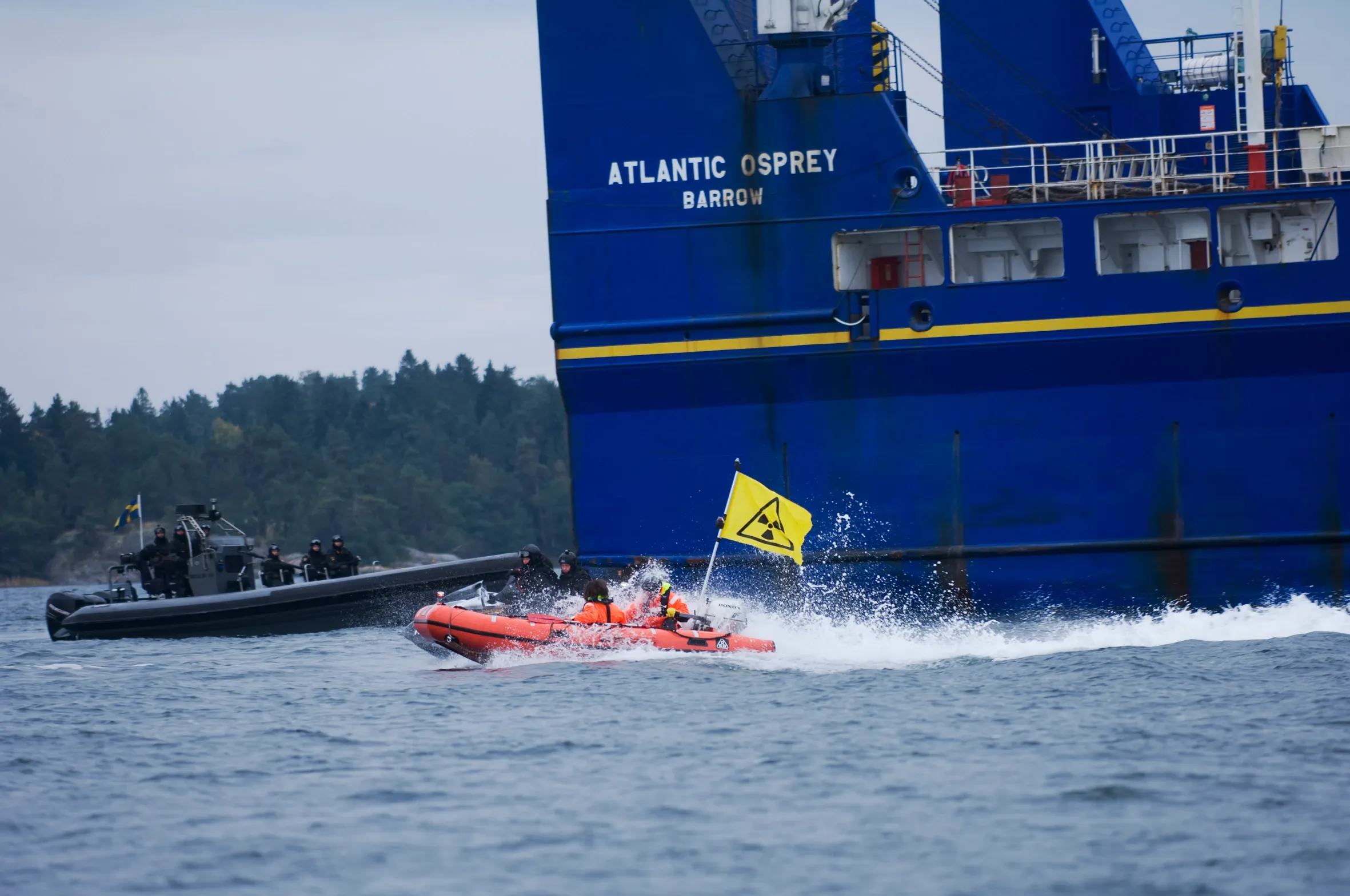 Small boat with yellow flag in front of a large blue ship