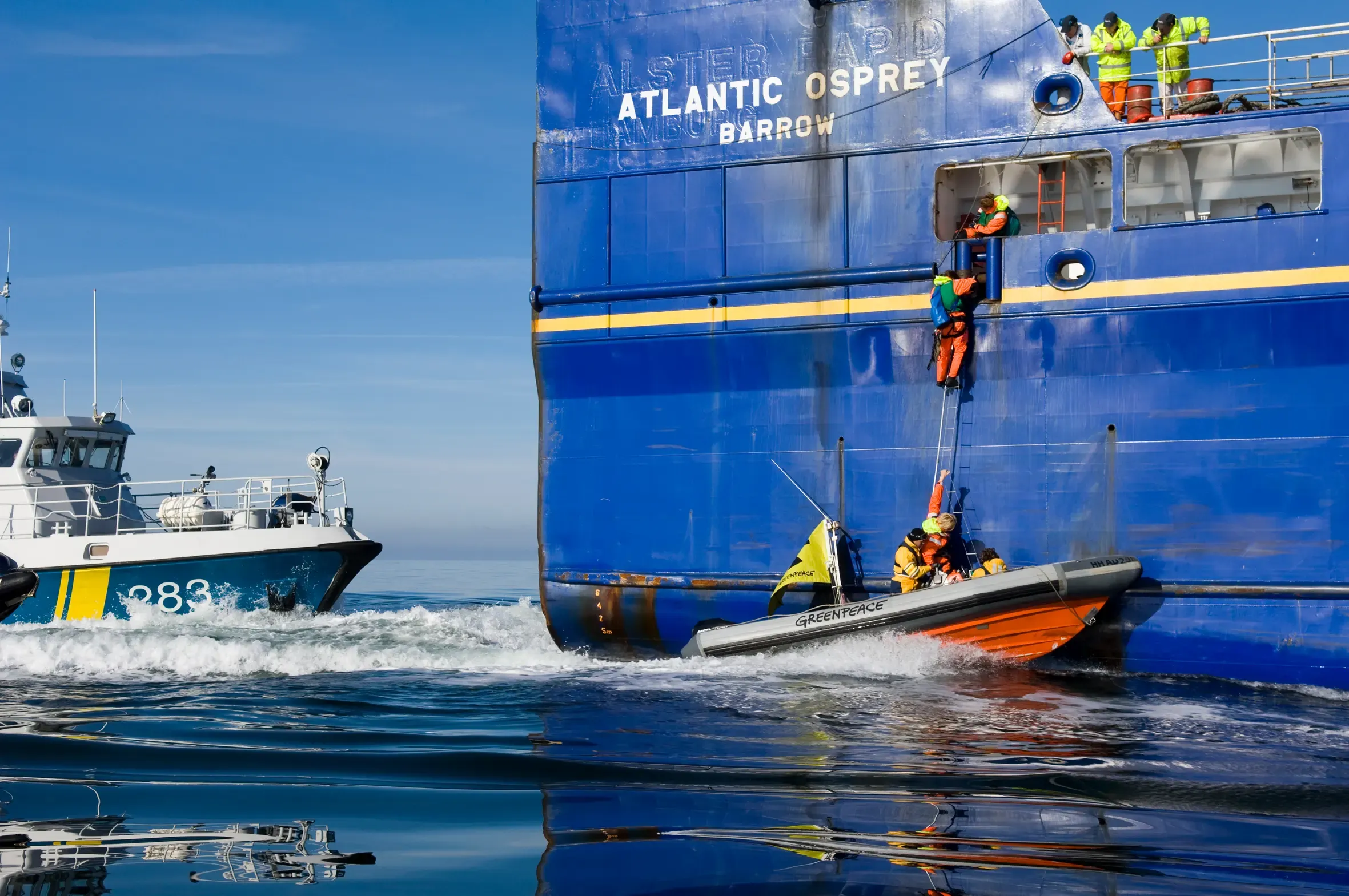 Small boat in front of a large blue ship on the ocean