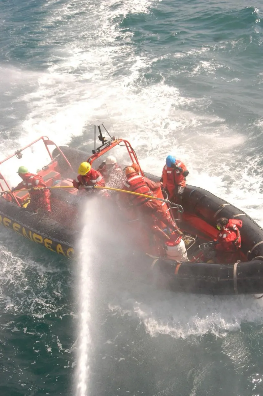 Crew on a boat getting sprayed with ocean water during high-speed maneuver