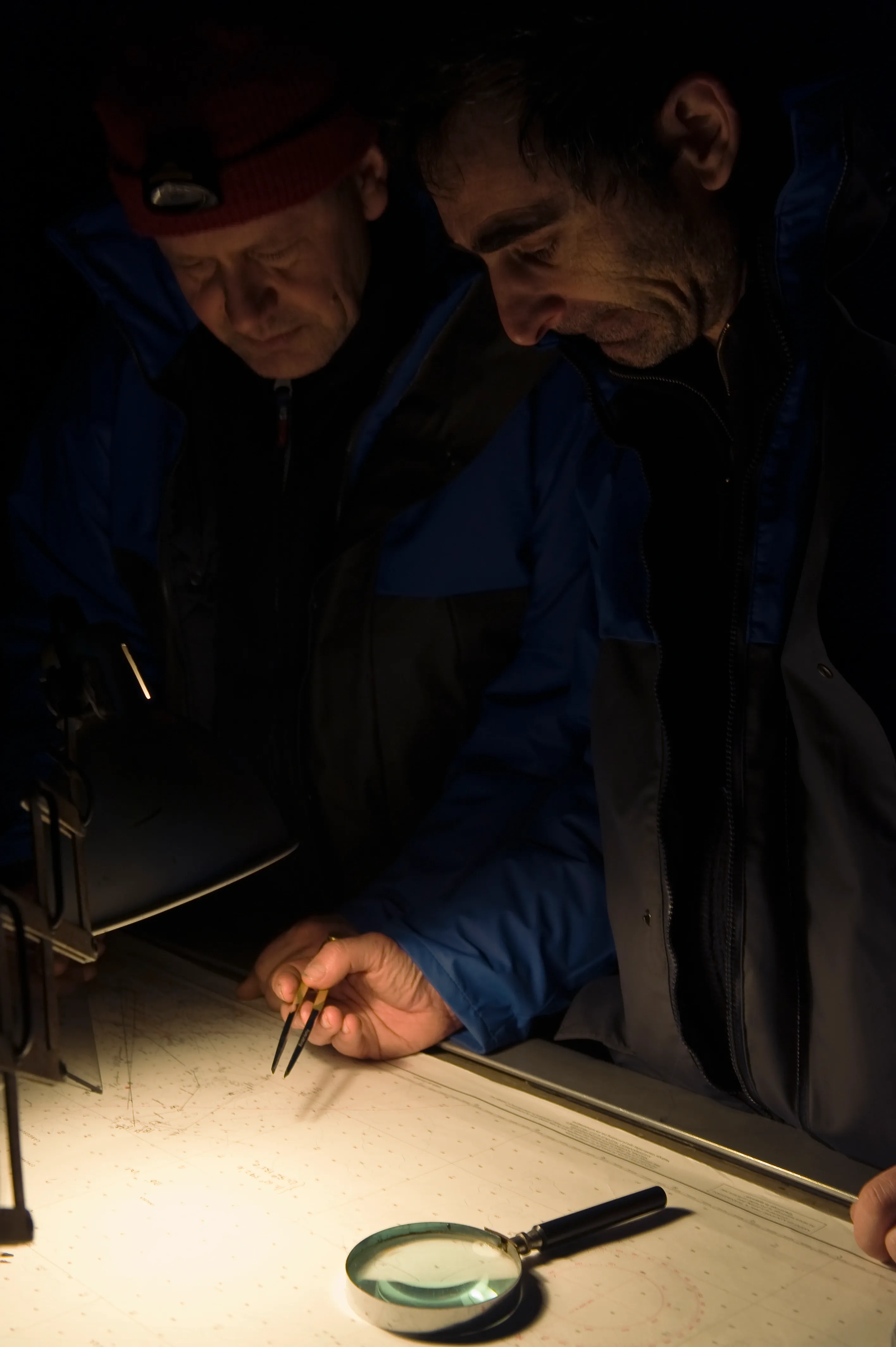 Maritime crew examining a sea chart with navigation equipment